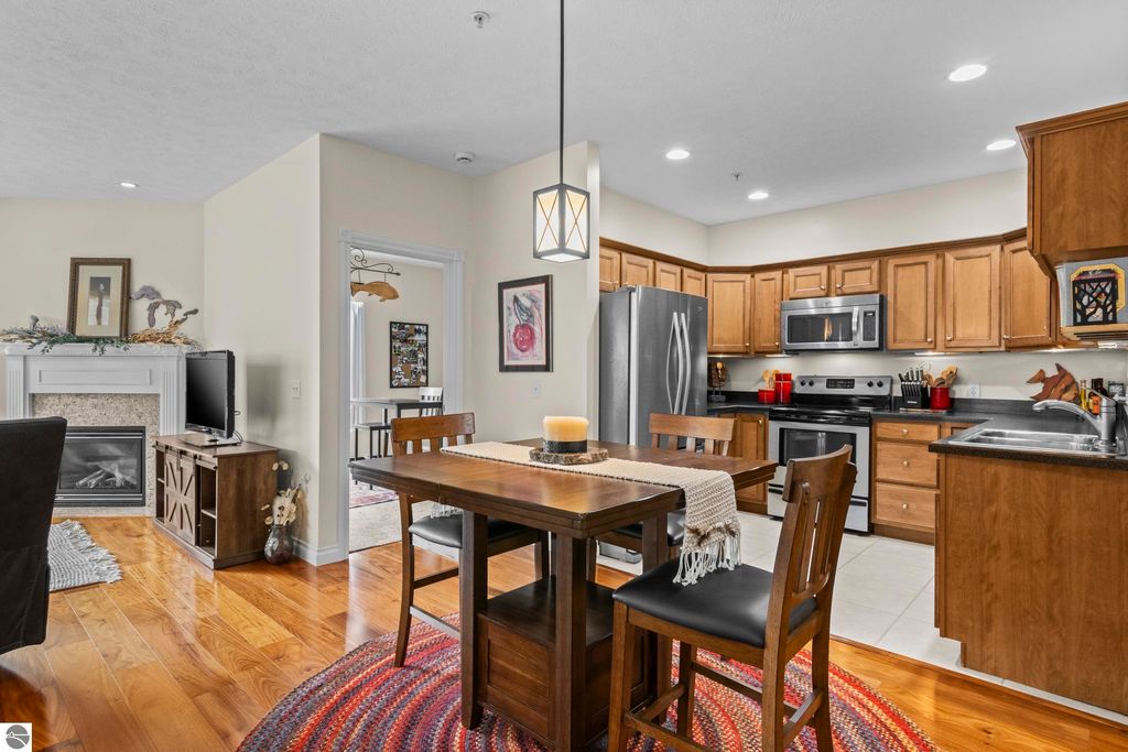 Cozy kitchen and dining area in a 2-bedroom, 2-bath condo at 1420 Forest Park Drive, featuring wood floors, stainless steel appliances, and a gas fireplace, ideal for comfortable living near downtown Traverse City.
