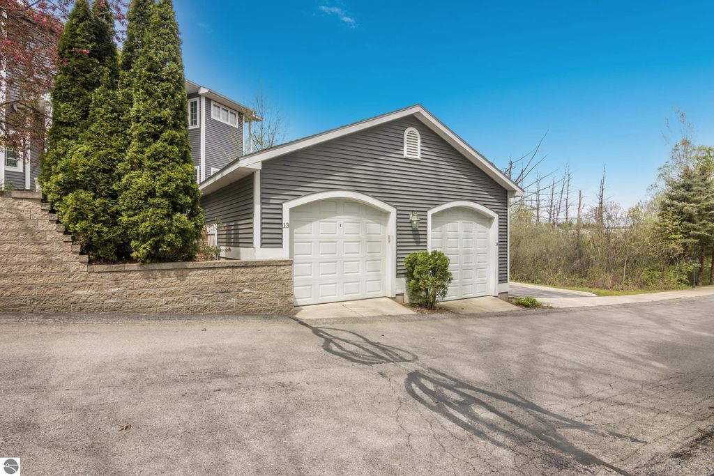 Condo garage at 1420 Forest Park Drive #13, Traverse City, featuring two doors, surrounded by greenery and a peaceful setting, ideal for convenient living near downtown.