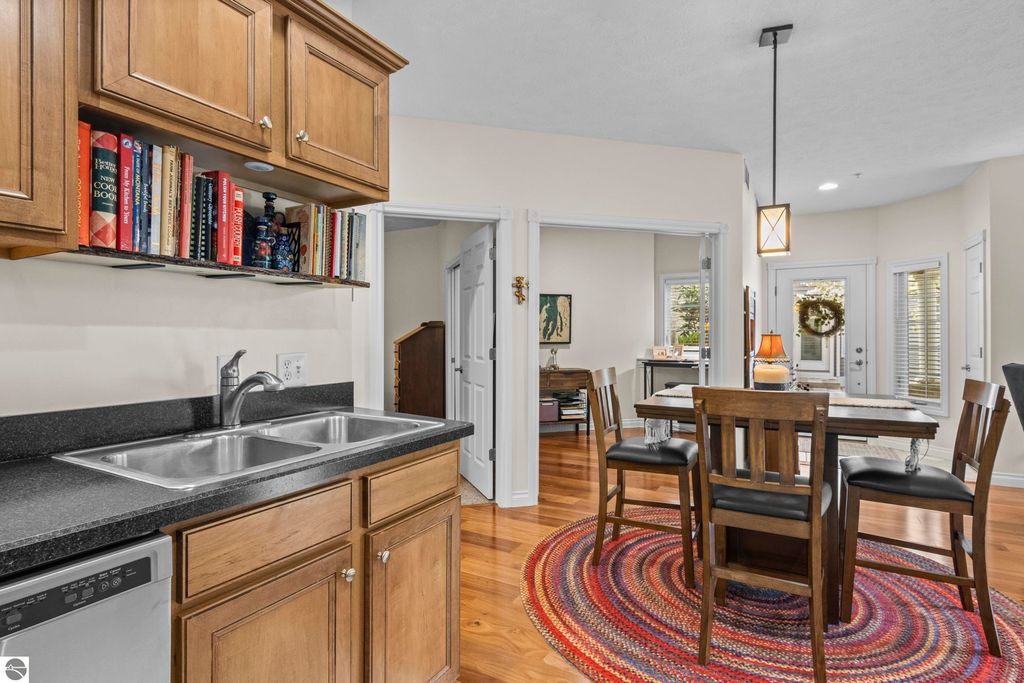 Kitchen area featuring wooden cabinets, double sink, and a dining table with chairs, showcasing an open floor plan in a 2-bedroom condo at 1420 Forest Park Drive, Traverse City, MI.