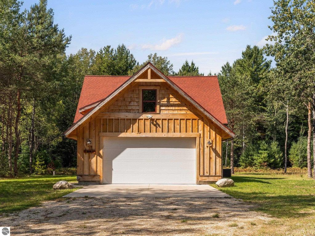 Custom-built home at 5800 W Moorestown Road, Lake City, MI, featuring wooden exterior, red roof, and garage, set on 10 acres of northern Michigan countryside.