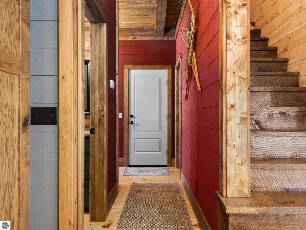 Custom-built home interior hallway featuring red and gray walls, wooden accents, a staircase, and a closed door, reflecting the craftsmanship and cozy atmosphere of the property at 5800 W Moorestown Road, Lake City, MI.