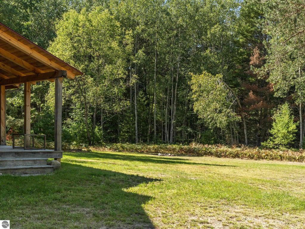 Covered porch of a custom-built home overlooking lush northern Michigan woods, showcasing a serene outdoor space ideal for relaxation and wildlife observation.