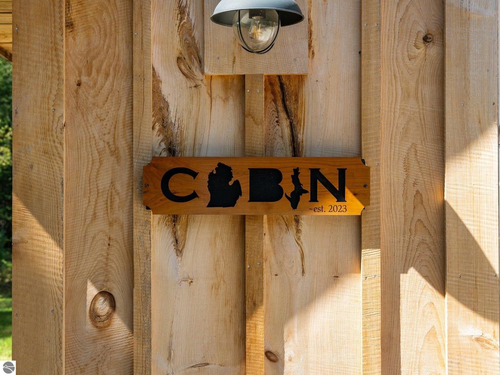 Cabin sign featuring the word "CABIN" with Michigan silhouette, established 2023, mounted on wooden wall, reflecting northern Michigan's rustic charm.