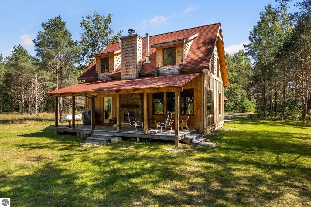 Custom-built 4-bedroom, 2-bath home with wooden exterior, covered porch, and large windows, set on 10 acres in northern Michigan countryside.