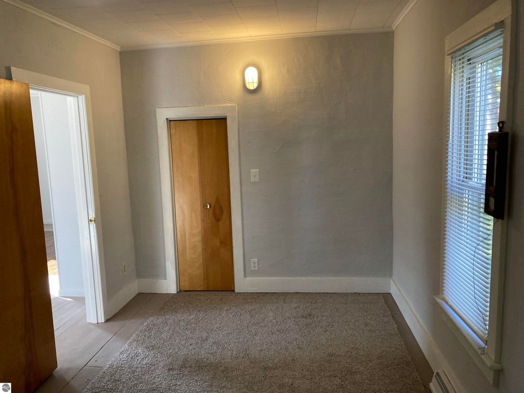 Cozy interior space of a home in Rose City, featuring a light gray wall, carpeted floor, and doors leading to other rooms, ideal for showcasing the property's inviting atmosphere.