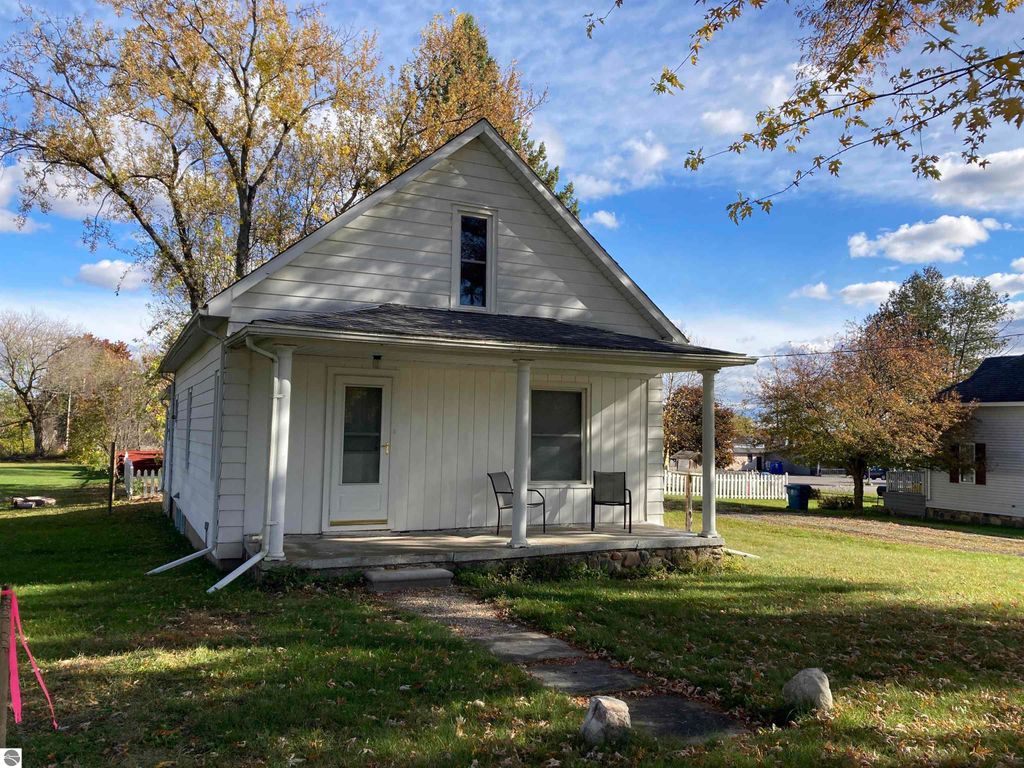 Cozy single-family home exterior at 206 George Smith Jr. Street, Rose City, MI, featuring a covered front porch, large yard, and nearby trees, showcasing a peaceful suburban setting.