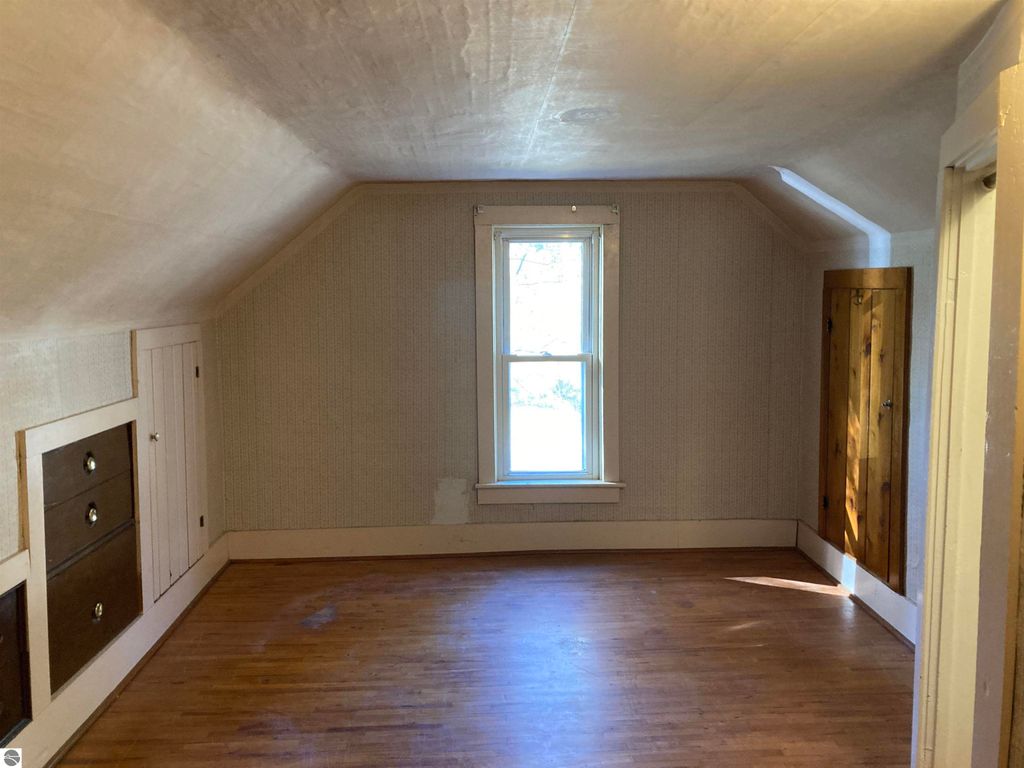 Cozy interior of a three-bedroom home in Rose City, featuring a window with natural light, hardwood floors, and built-in storage, ideal for potential buyers.