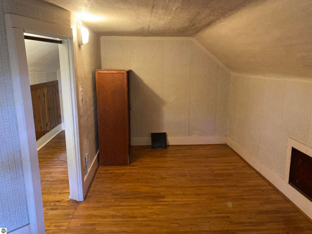 Cozy interior view of a three-bedroom home in Rose City, featuring hardwood floors, a closet, and an angled ceiling, showcasing potential living space.