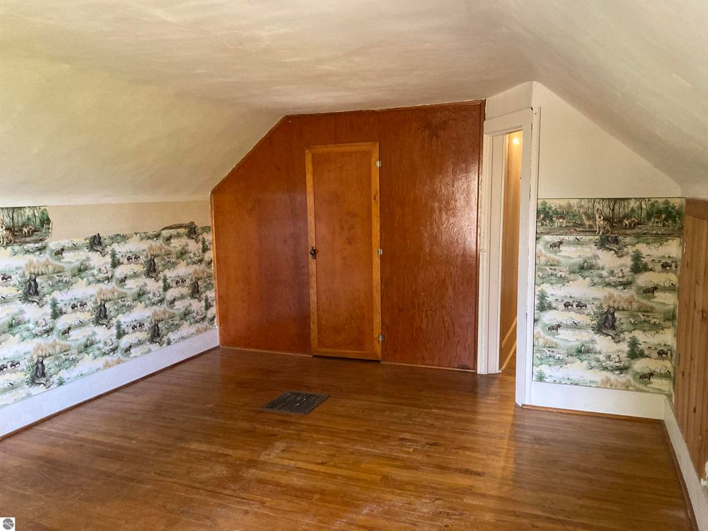 Interior view of a cozy room in a home at 206 George Smith Jr. Street, featuring wooden flooring, a sloped ceiling, and nature-themed wallpaper.
