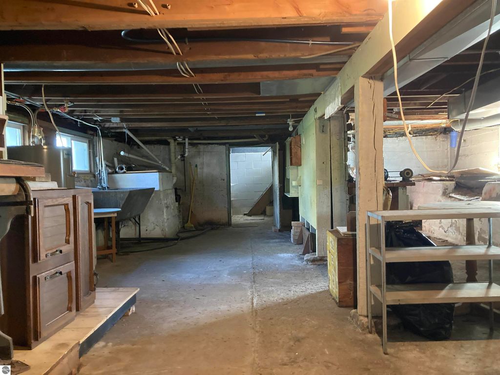 Basement interior of cozy home in Rose City, featuring exposed beams, storage areas, and utility space, showcasing potential for mechanicals and storage solutions.