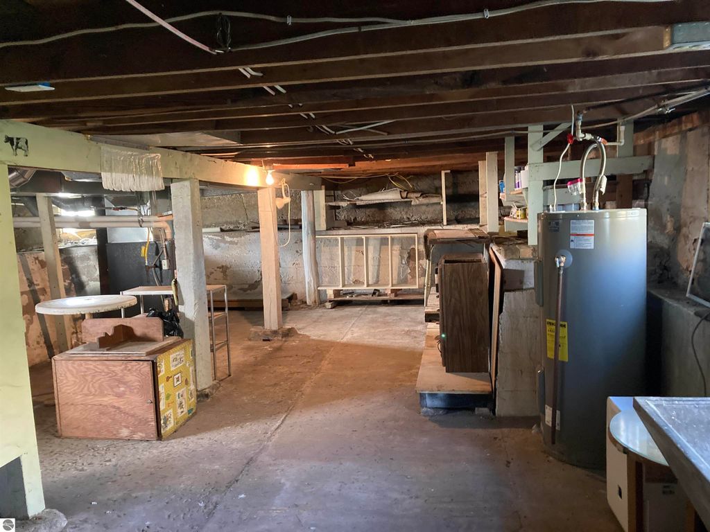 Basement interior of a home in Rose City, featuring storage areas, a water heater, and exposed beams, showcasing potential for mechanicals and storage solutions.