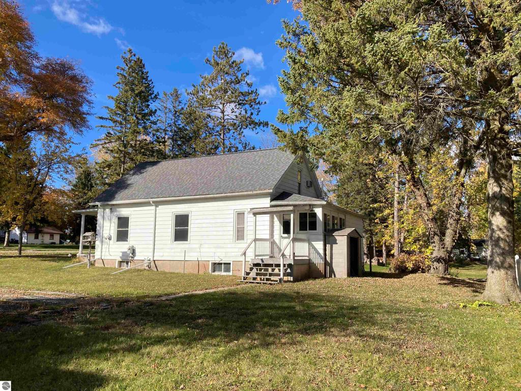 Cozy single-family home in Rose City, MI, featuring a covered front porch, enclosed back porch, and surrounded by trees in a quiet neighborhood.