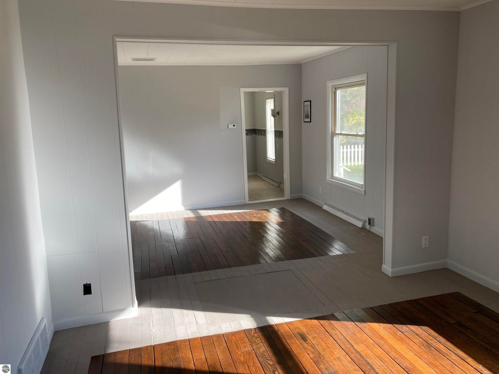 Interior view of cozy home at 206 George Smith Jr. Street, showcasing wood floors and natural light, highlighting living space and access to kitchen and dining areas.