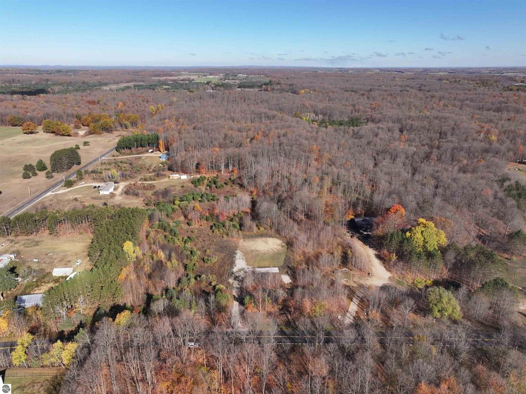 Aerial view of 8-acre wooded parcel in Buckley, MI, showcasing cleared area for building, surrounding nature, and proximity to recreational trails.