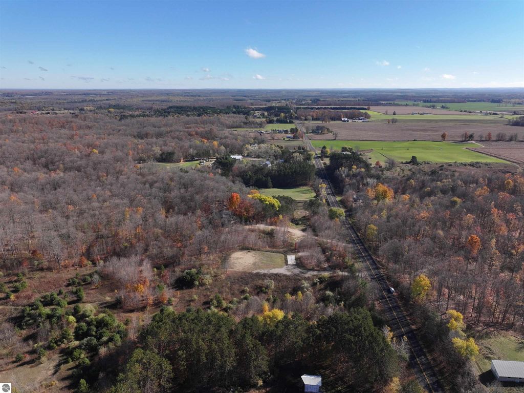 Aerial view of 8-acre wooded parcel at 6884 Zue Road, Buckley, MI, showcasing natural landscape, cleared area for building, and proximity to recreational trails.