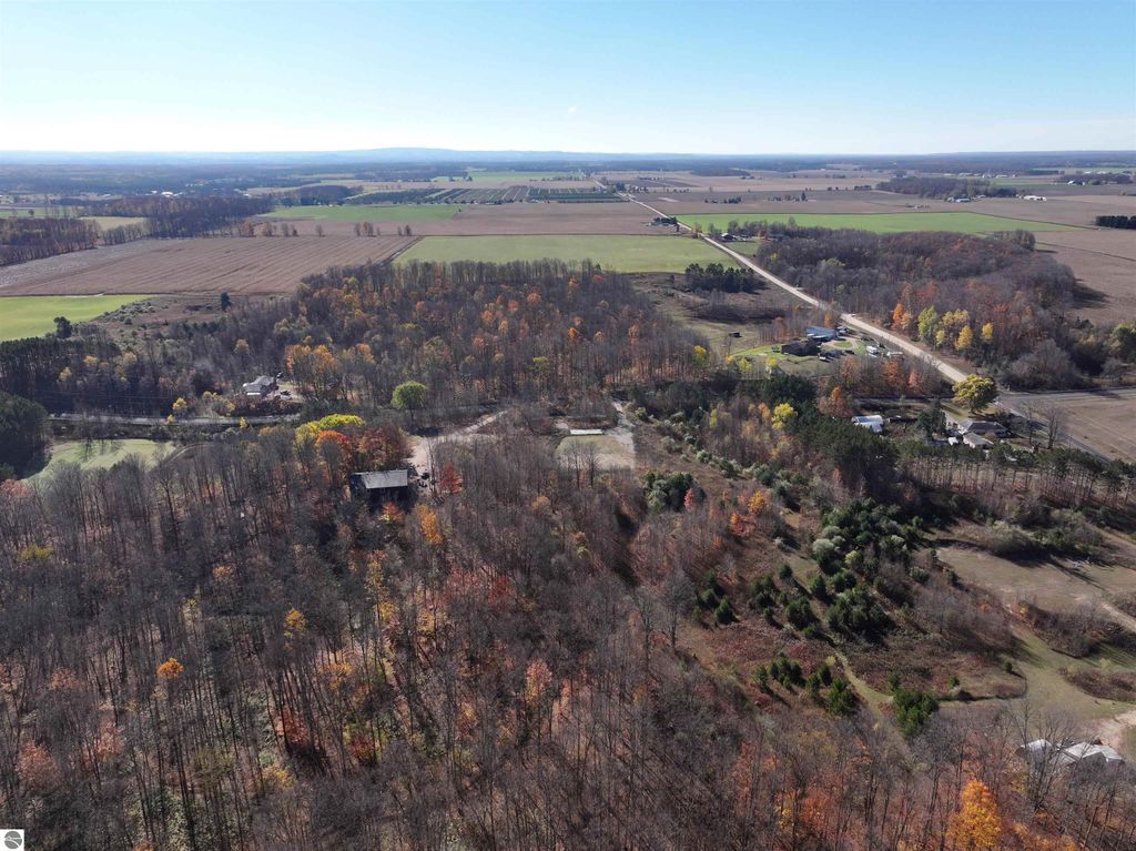 Aerial view of 8-acre wooded parcel at 6884 Zue Road, Buckley, MI, showcasing natural landscape, established trees, and cleared area for building, emphasizing privacy and recreational potential.