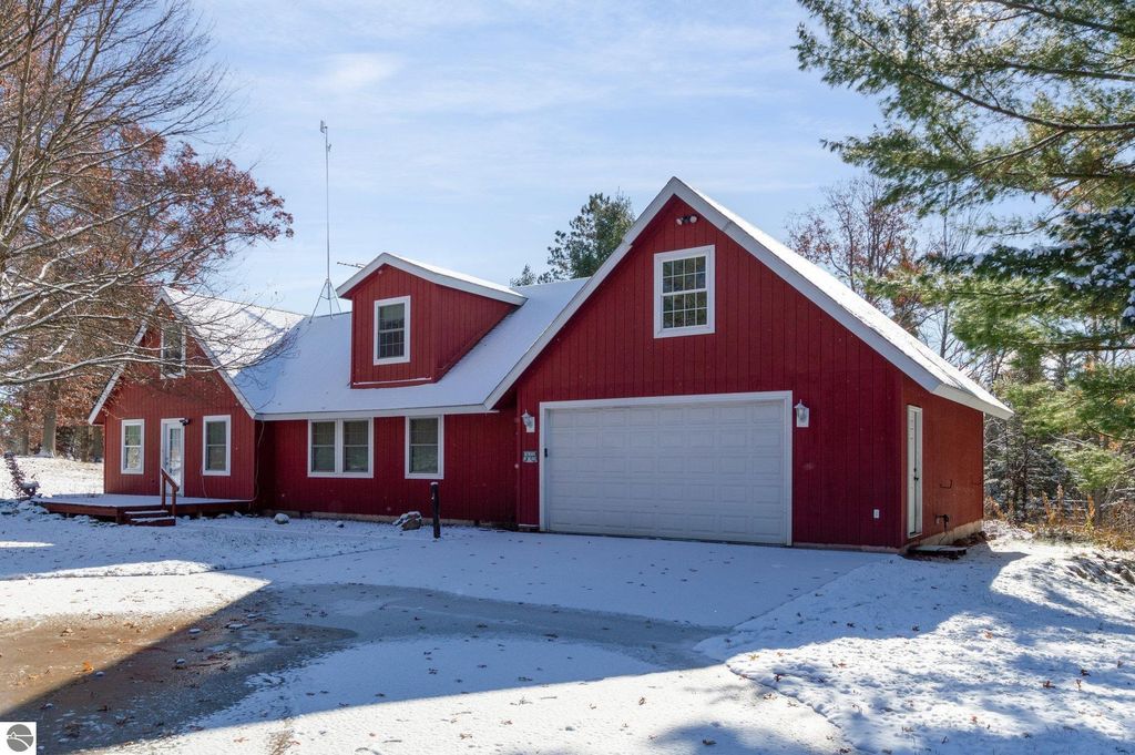 Spacious red house with a garage and snow-covered yard, showcasing the exterior of the 4-bedroom home at 650 Linda Drive, Harrison, MI, ideal for year-round living or seasonal retreats.