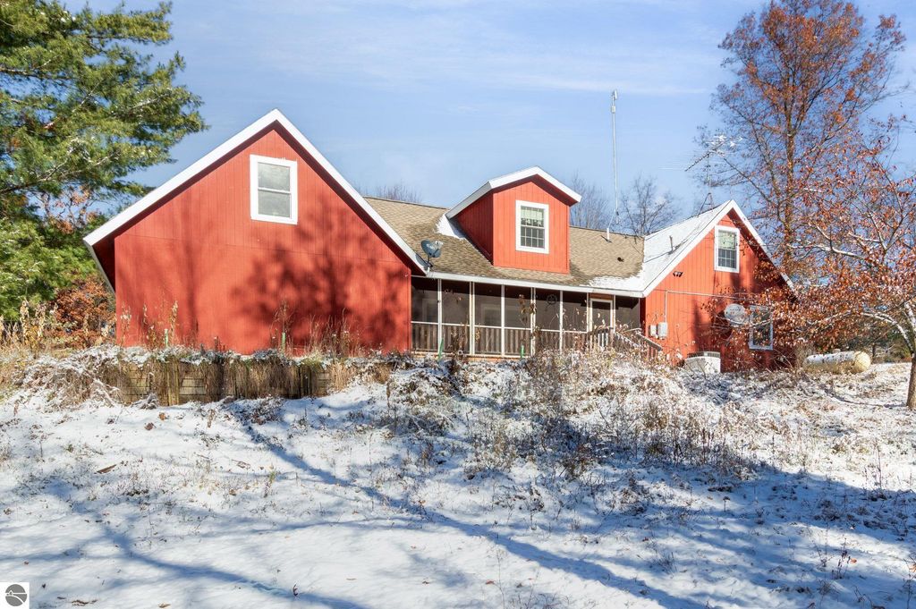 Spacious red two-story home with screened-in porch and snowy landscape, located at 650 Linda Drive, Harrison, MI, ideal for year-round living or seasonal retreat.