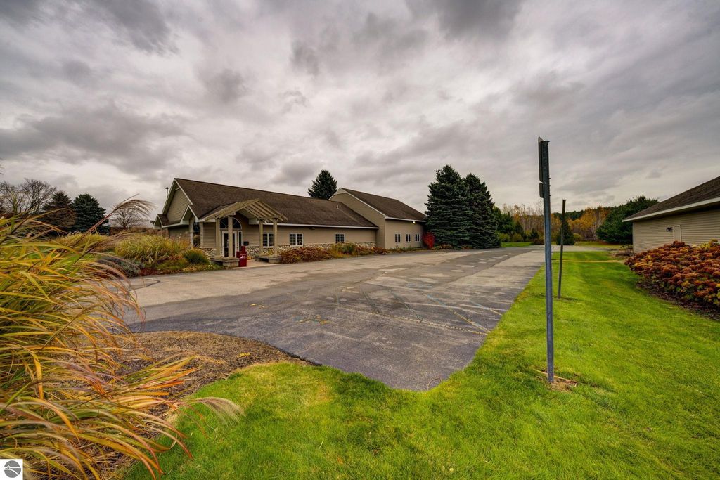 Commercial property exterior at 7200 E Duck Lake Road, Lake Leelanau, featuring two buildings, landscaped surroundings, and ample parking space, highlighting investment potential in a growing community.