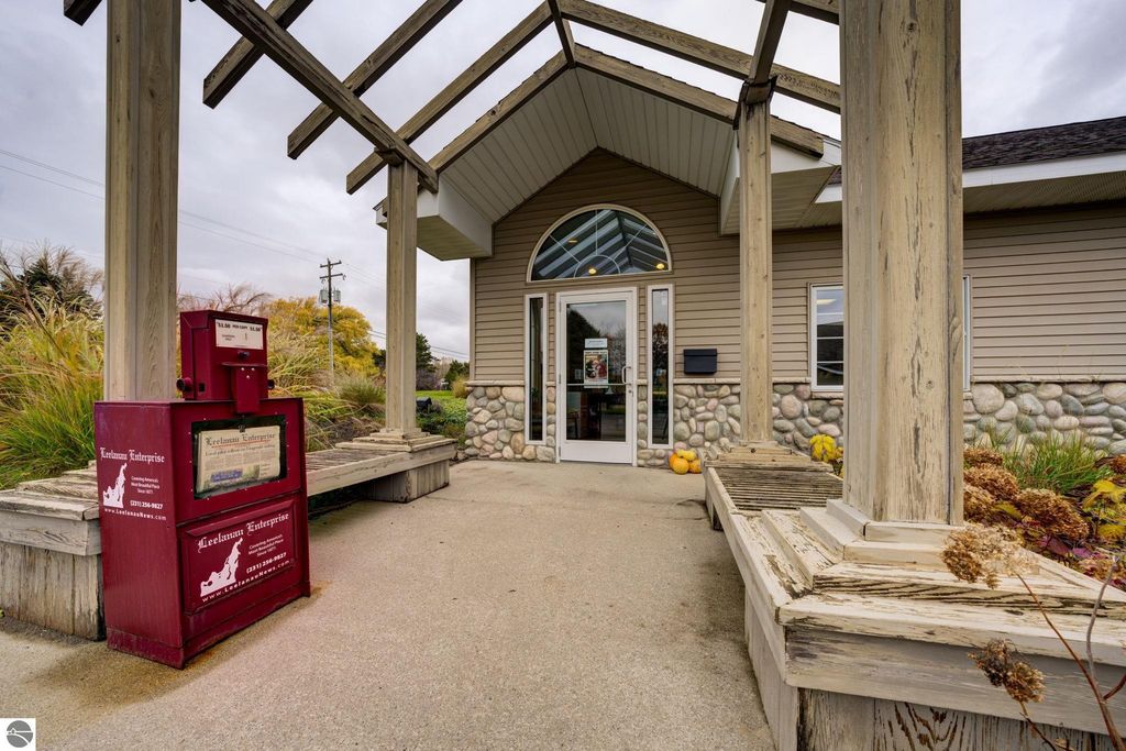 Commercial building entrance at 7200 E Duck Lake Road, featuring the Leelanau Enterprise newspaper box, landscaped porch, and stone foundation, highlighting investment opportunity in Lake Leelanau.
