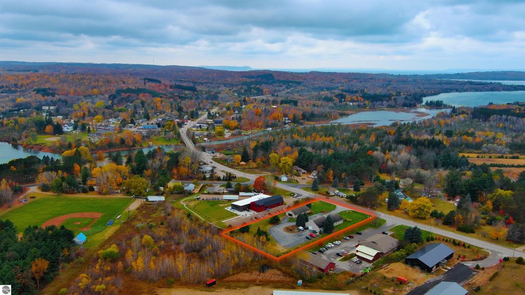 Aerial view of Lake Leelanau, showcasing commercial properties, residential areas, and surrounding autumn foliage, highlighting investment opportunities along the high-visibility business corridor near 7200 E Duck Lake Road.