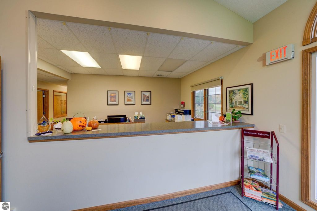 Reception area of commercial property at 7200 E Duck Lake Road, featuring a service counter, decorative pumpkins, framed artwork, and an exit sign.