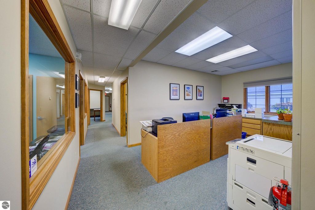 Office interior featuring reception area with wooden partitions, desks, and framed artwork, illustrating workspace layout for commercial property at 7200 E Duck Lake Road, Lake Leelanau, MI.
