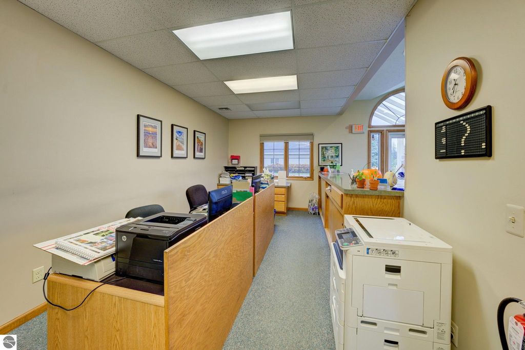 Office interior featuring a reception area with printer, desks, and artwork, highlighting a commercial space available for lease in Lake Leelanau, MI.