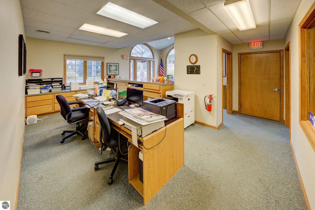 Office interior featuring multiple desks, computers, and office supplies, highlighting a functional workspace in the commercial property at 7200 E Duck Lake Road, Lake Leelanau, MI.
