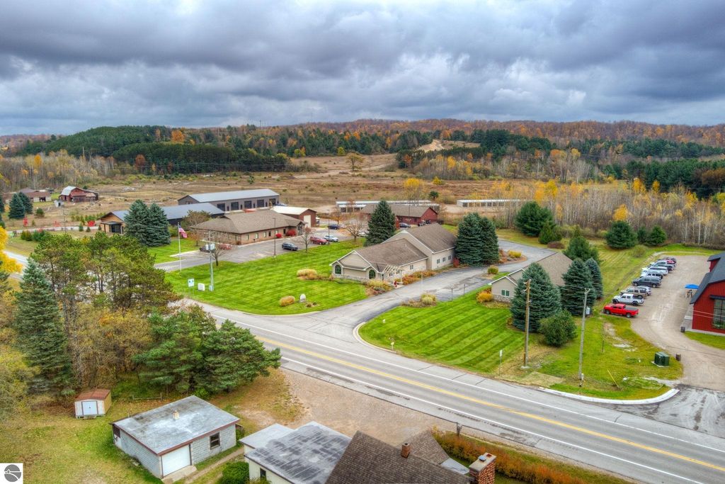 Aerial view of commercial property at 7200 E Duck Lake Road, Lake Leelanau, featuring two buildings, landscaped grounds, and surrounding autumn foliage.