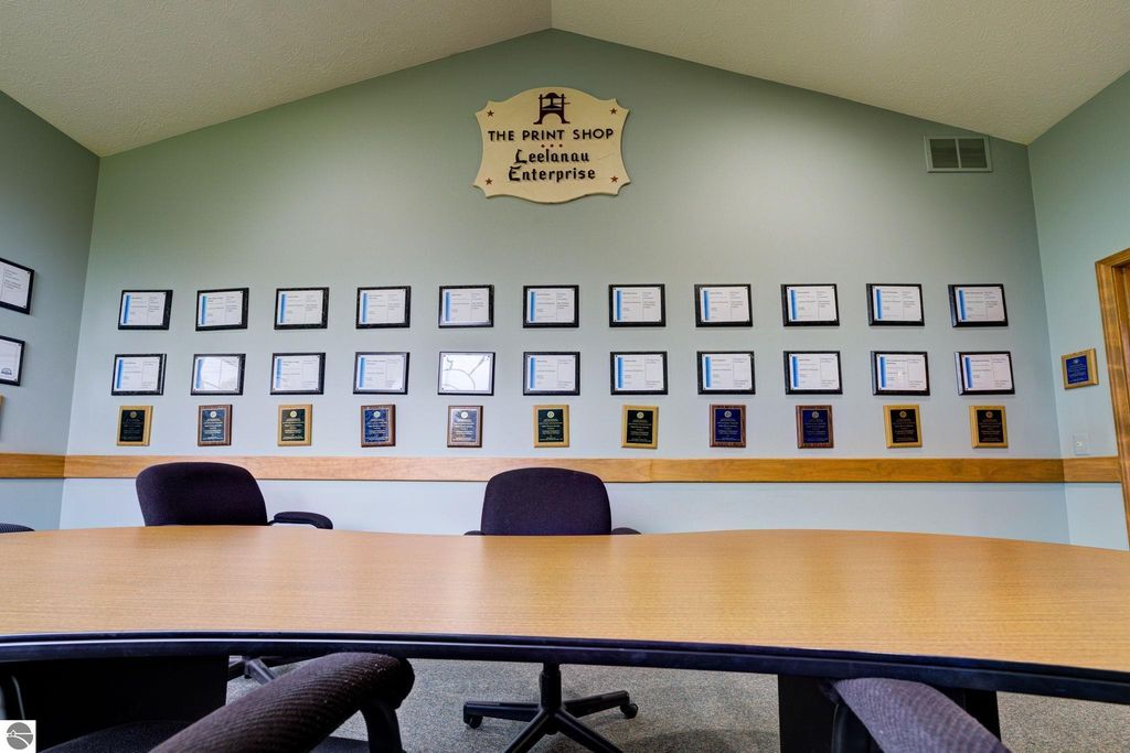 Conference room interior featuring a round table and a wall adorned with various plaques and certificates, showcasing achievements of Leelanau Enterprise, located in Lake Leelanau, MI.