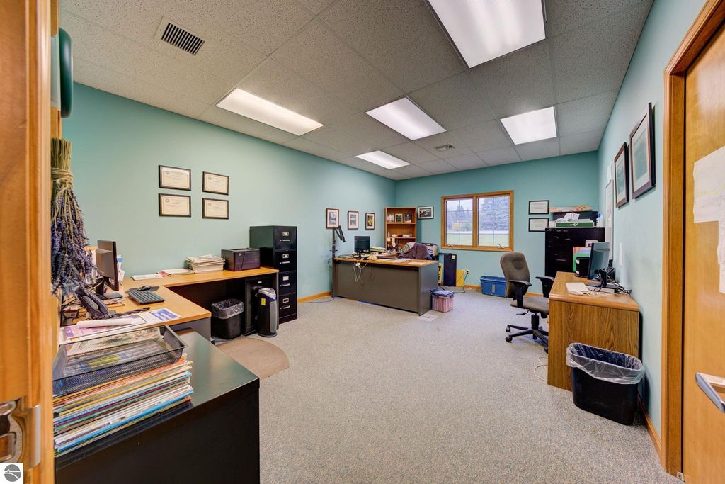 Office interior with desks, filing cabinets, and computers, showcasing a professional workspace in a commercial property listing for 7200 E Duck Lake Road, Lake Leelanau, MI.