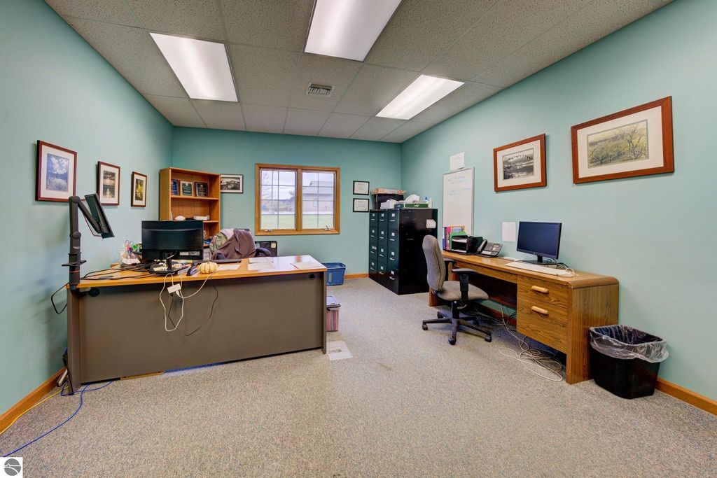 Office interior featuring two desks, computer setups, filing cabinets, and wall art, representing workspace within commercial property at 7200 E Duck Lake Road, Lake Leelanau, MI.