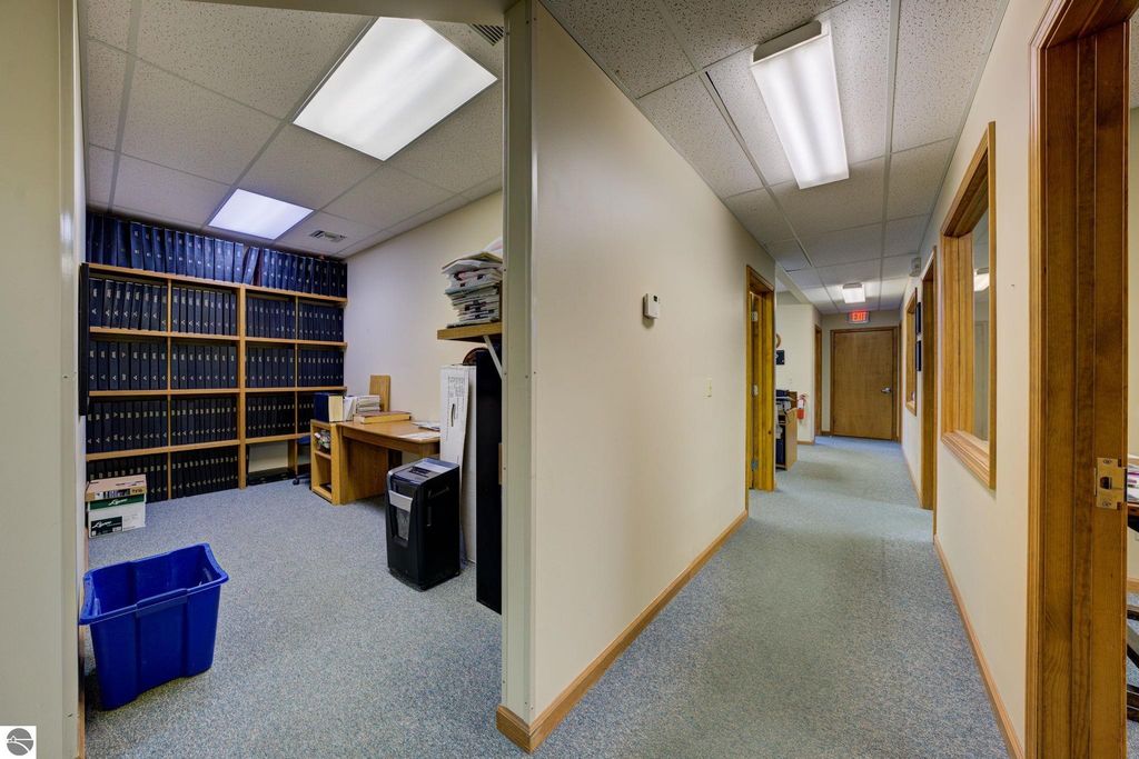 Office interior featuring a hallway leading to a room with a desk, filing cabinets, and office supplies, highlighting workspace potential in commercial real estate listing at 7200 E Duck Lake Road, Lake Leelanau.