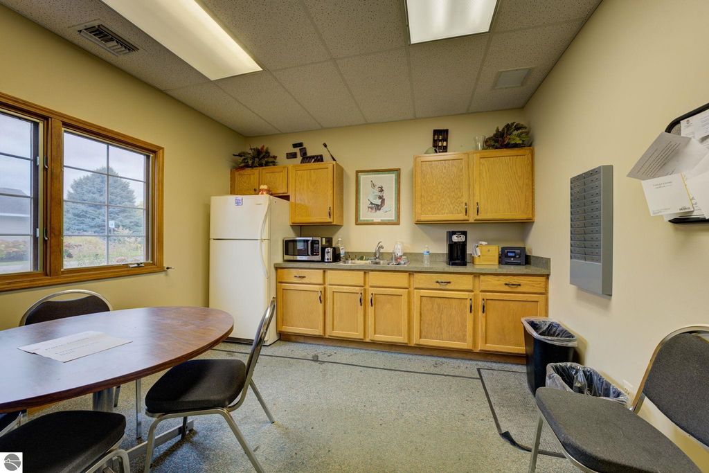 Kitchen area in commercial property at 7200 E Duck Lake Road, featuring wooden cabinets, refrigerator, coffee maker, and a round table with chairs, highlighting functional workspace for tenants.