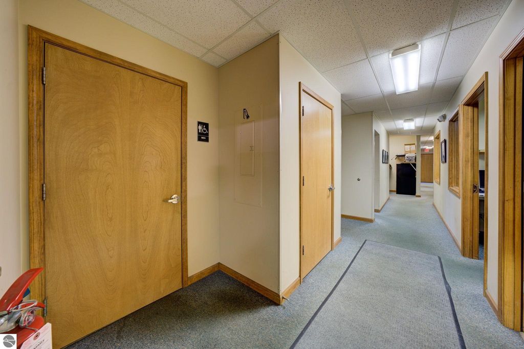 Hallway view inside a commercial building at 7200 E Duck Lake Road, featuring wooden doors, office signage, and carpeted flooring, illustrating the interior layout and potential office space for lease.