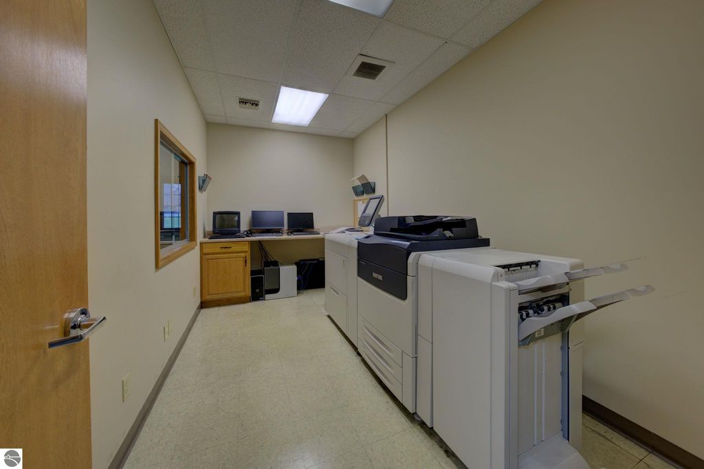 Office space featuring a multifunction printer, two computer workstations, and a storage cabinet, indicative of commercial property amenities at 7200 E Duck Lake Road, Lake Leelanau, MI.