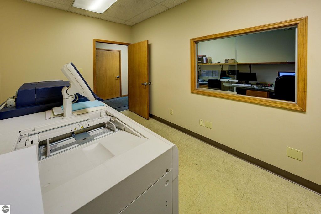 Office interior featuring a copier and a view into an office space with computers and chairs, relevant to commercial real estate listing at 7200 E Duck Lake Road, Lake Leelanau, MI.