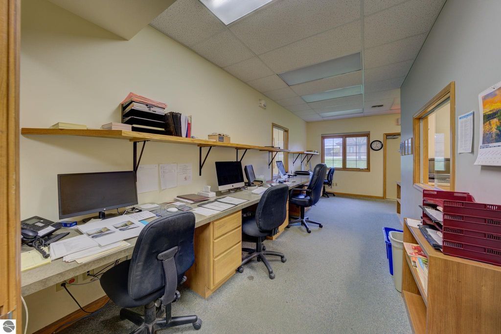 Office interior with multiple workstations, computers, and shelves, showcasing a commercial space at 7200 E Duck Lake Road, Lake Leelanau, MI, relevant to real estate investment opportunities.