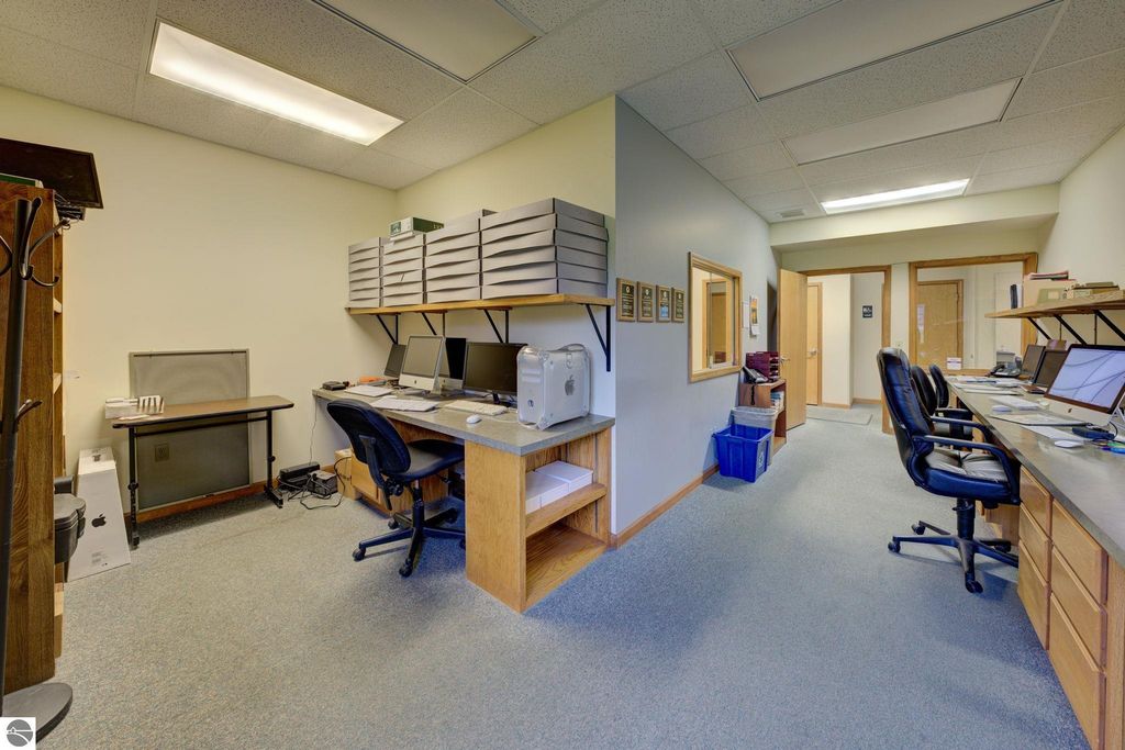 Office interior with multiple workstations, computers, and storage, showcasing a reception area and office setup in a commercial building for sale at 7200 E Duck Lake Road, Lake Leelanau, MI.