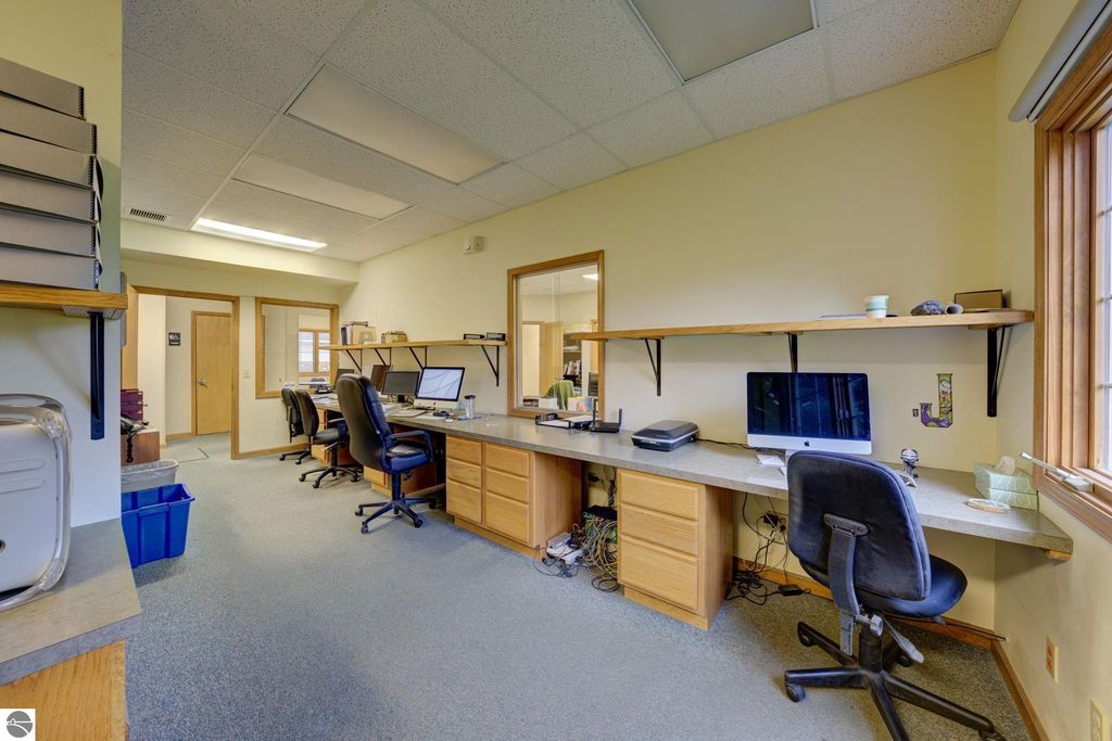 Office workspace featuring multiple desks with computers, ergonomic chairs, and shelving, highlighting a professional environment suitable for business operations in Lake Leelanau.