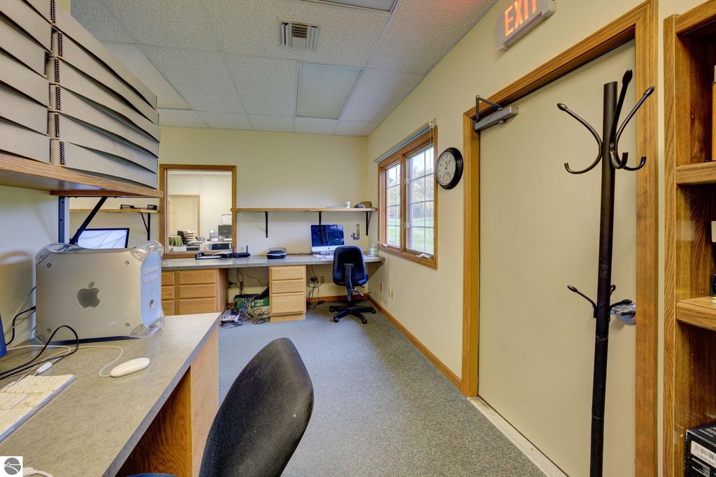 Office interior featuring a desk with computer, storage boxes, and a coat rack, illustrating workspace potential for commercial property at 7200 E Duck Lake Road, Lake Leelanau, MI.