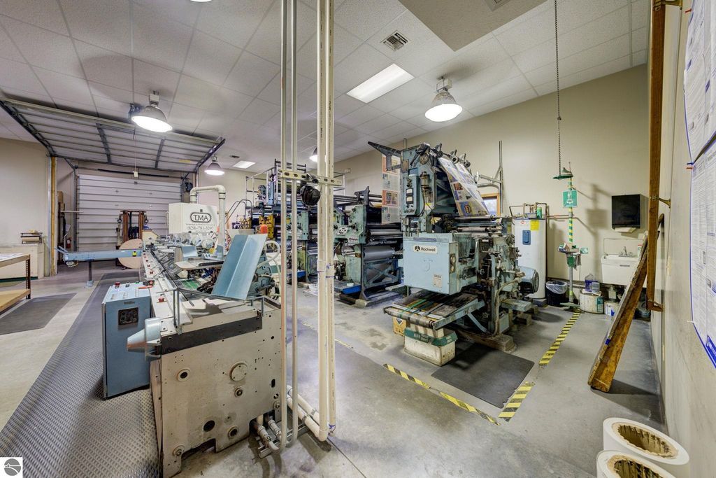 Printing machinery and production equipment inside a commercial building at 7200 E Duck Lake Road, Lake Leelanau, MI, showcasing workspace for manufacturing and production activities.