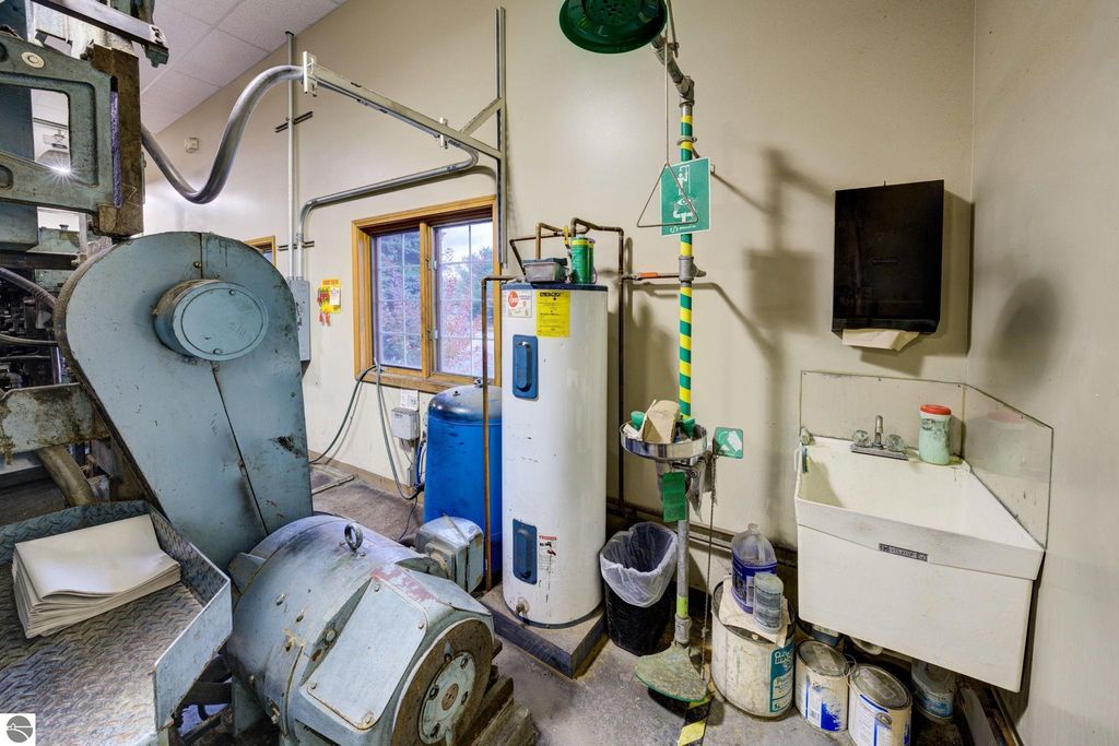 Industrial workspace featuring machinery, a sink, safety equipment, and storage areas, relevant to commercial real estate listing at 7200 E Duck Lake Road, Lake Leelanau, MI.