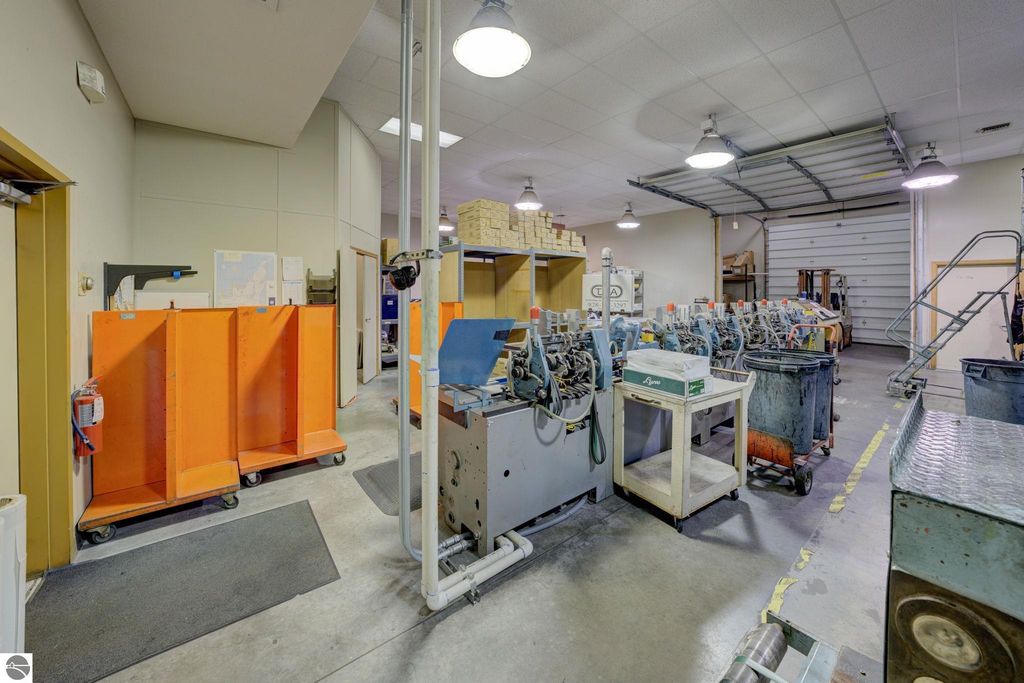 Interior view of commercial production space with machinery, storage areas, and orange dividers, highlighting flexible potential in Lake Leelanau property listing.
