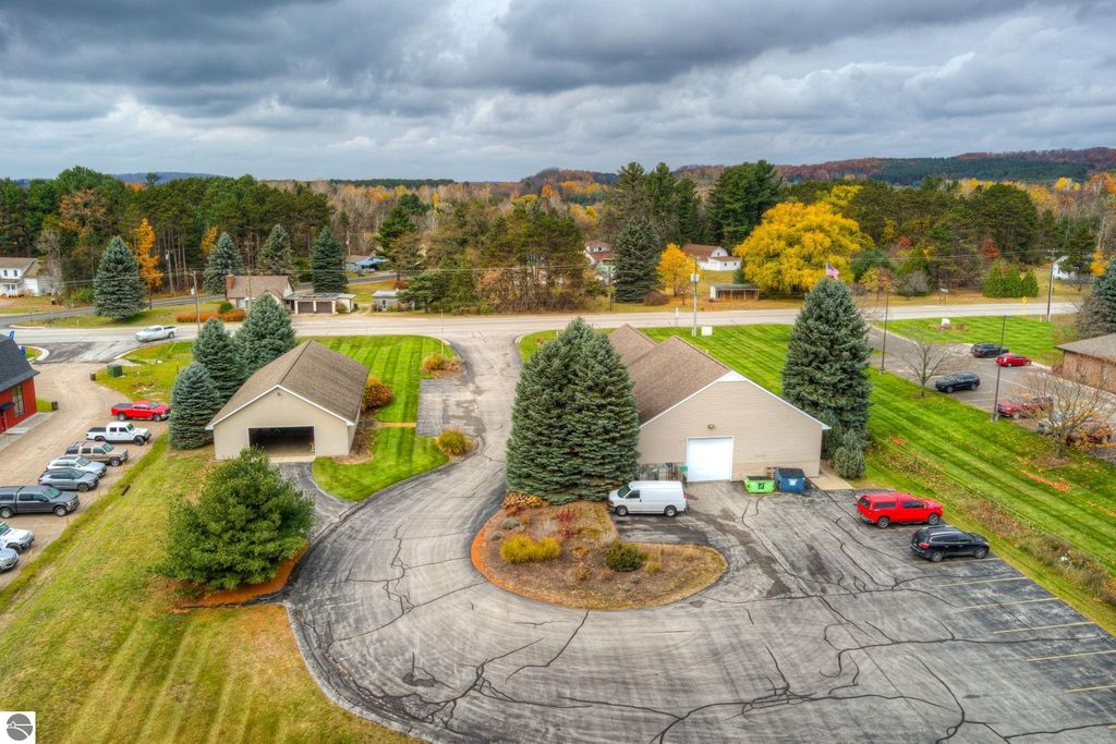 Aerial view of commercial property at 7200 E Duck Lake Road, Lake Leelanau, featuring two buildings, parking area, and landscaped surroundings, highlighting investment opportunity in a growing community.