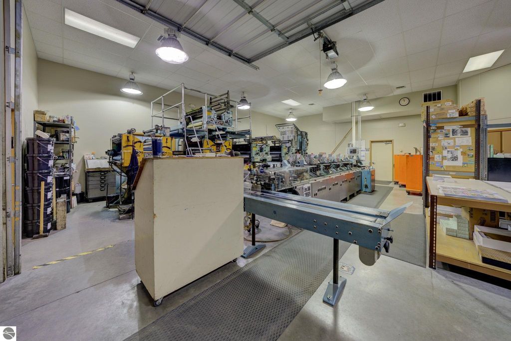 Commercial printing production area with machinery, workstations, and storage shelves, showcasing a leased space at 7200 E Duck Lake Road, Lake Leelanau, MI.