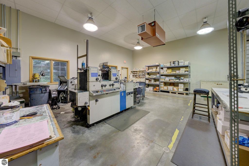 Commercial workspace interior featuring printing machinery, workstations, and storage shelves, highlighting the property&rsquo;s manufacturing potential at 7200 E Duck Lake Road, Lake Leelanau, MI.