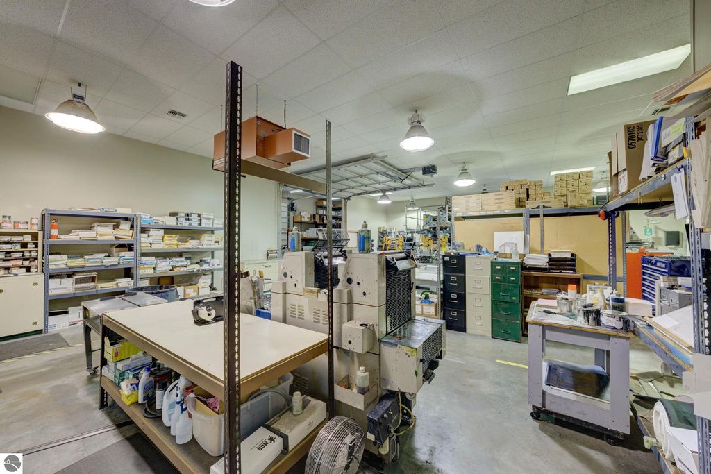 Interior view of commercial workspace with shelving, workstations, and printing machinery, showcasing flexible storage and production areas in Lake Leelanau.