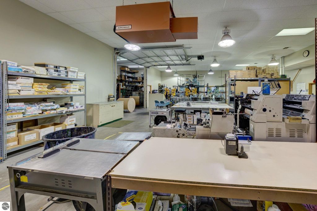 Commercial printing workspace with production equipment, storage shelves filled with paper, and a spacious layout, reflecting the operational environment of the leased building at 7200 E Duck Lake Road, Lake Leelanau, MI.